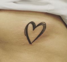 a woman's stomach with a black heart tattoo on her left side ribcage