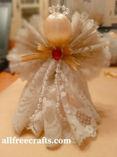 an angel made out of lace and pearls on top of a table next to a computer