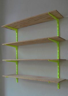 three wooden shelves with neon green brackets on the sides and one shelf has no doors