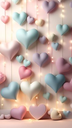 many heart shaped balloons hanging from strings against a wall with lights in the shape of hearts