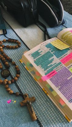 an open bible on a table next to a cross and rosary with other items nearby