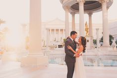 a bride and groom kissing in front of a fountain