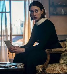 a woman sitting in a chair holding a piece of paper