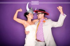 a man and woman posing for a photo in front of a purple background with horns on their heads