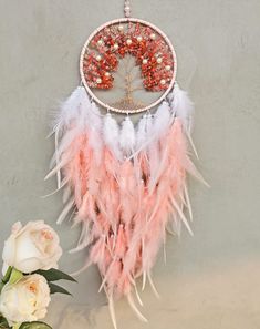 a pink and white dream catcher next to a bouquet of flowers on a gray wall