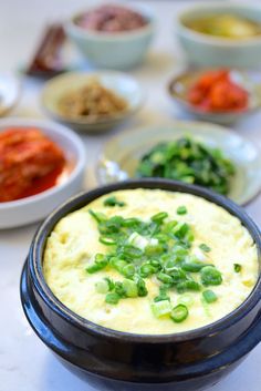 there are many different bowls of food on the table, including dips and sauces