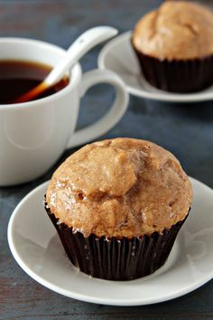 a muffin sitting on top of a white plate next to a cup of coffee