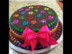 a large cake with chocolate frosting and colorful decorations on the top is decorated with pink bows