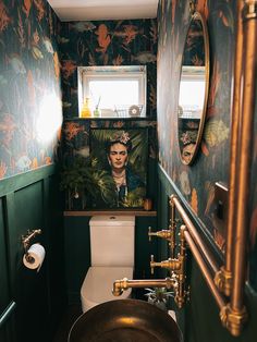 the bathroom is decorated in green and gold with an art work on the wall above the toilet