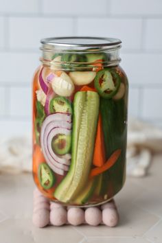 a mason jar filled with pickles, onions, carrots and celery