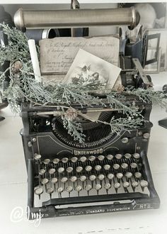 an old - fashioned typewriter is decorated with greenery and cards for the holiday season