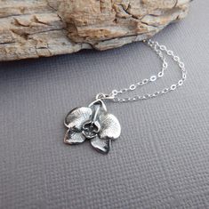 sterling silver orchid flower necklace, 5/8" - A sterling silver charm, measuring 5/8" (15 mm) in length and across.   - Necklace is 1.5 mm cable chain, with lobster clasp and locking jump rings, all solid sterling silver.  - Charm has blackening (oxidizing) to bring out the details. - Flower is realistic looking, back has textured detail. - Packaged in a modern circular tin, ready for gift giving, and comes with a silver polish pad and care instructions. Customize chain length or "charm only" o Silver Polish, Top Rings, Botanical Jewelry, Floral Pendant, Orchid Flower, Flower Jewellery, Last Minute Gifts, Flower Necklace, Sterling Silver Charm