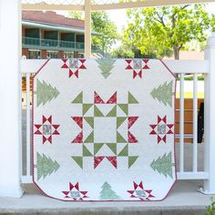 a white porch with a red and green quilt on it