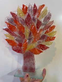 a hand holding up a glass sculpture made to look like a tree