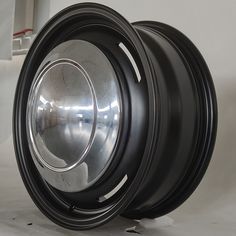 a close up of a black wheel on a white surface with holes in the center