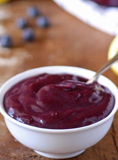 a white bowl filled with blueberry sauce on top of a wooden table