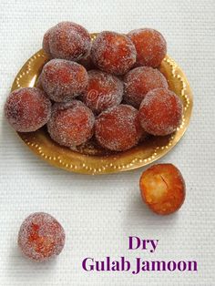 powdered sugar coated doughnuts on a gold plate with the words dry gulab jamon