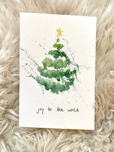 a card with a watercolor christmas tree on it that says joy to the world