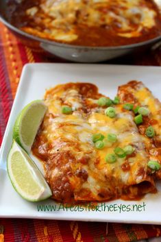 a white plate topped with enchiladas next to a skillet filled with sauce