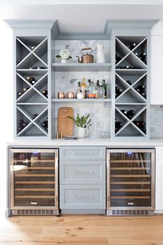 a kitchen with white cabinets and wine racks on the wall above it is an empty wooden floor