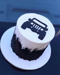 a black and white cake with a jeep on it's top is sitting on a plate