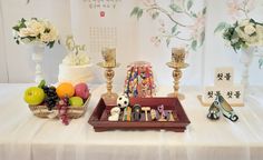 a table topped with fruit and candles on top of a white cloth covered tablecloth