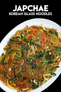 a white plate topped with noodles and veggies on top of a black table