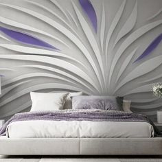 a large bed sitting in front of a wall with purple and white designs on it