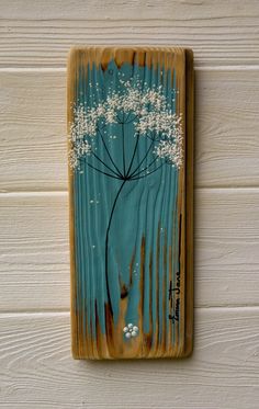 a painting on wood with white flowers painted on it