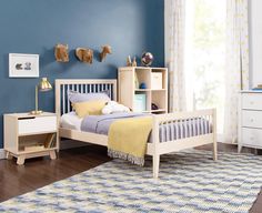 a child's bedroom with blue walls and wooden furniture, including a white bed