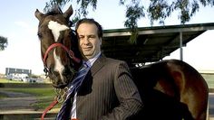 a man in a suit standing next to a horse