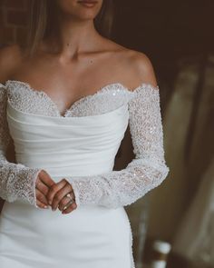 a woman in a white wedding dress holding her hands on her hips and looking off to the side