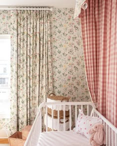 a baby's room with floral wallpaper and pink curtains, white crib