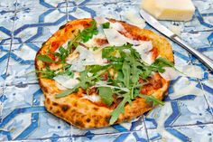 a pizza sitting on top of a blue and white tile floor next to a slice of cheese