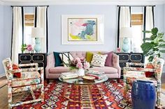 a living room filled with furniture and paintings on the wall above it's windows