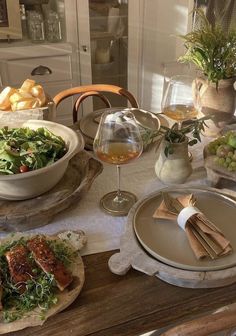 the table is set with food and wine for two people to enjoy it, including salad