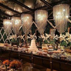 a long table with many different types of food on it and chandeliers hanging from the ceiling