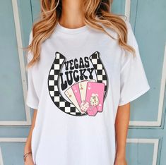 a woman standing in front of a blue wall wearing a white shirt that says vegas lucky