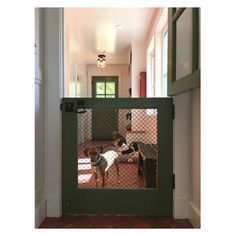 two dogs are sitting in their kennel at the entrance to an open door that leads into another room