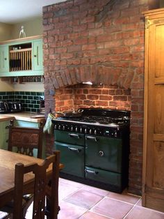 a kitchen with an oven, table and chairs next to a brick wall in the background