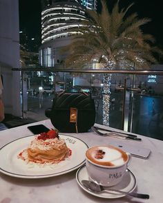 a table topped with a plate of food next to a cup of cappuccino