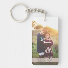 a keychain with an image of two children holding each other and the words sisters on it