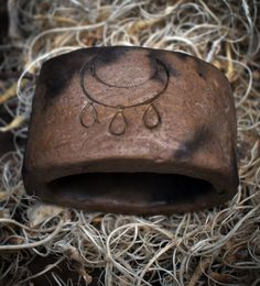 an old stone object with water drops on it's surface in some dry grass