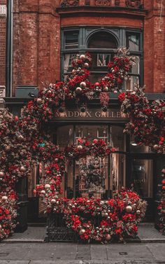 christmas wreaths on the outside of a storefront in front of a red brick building