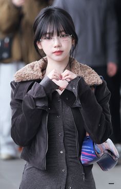 a woman with black hair and glasses is standing on the street