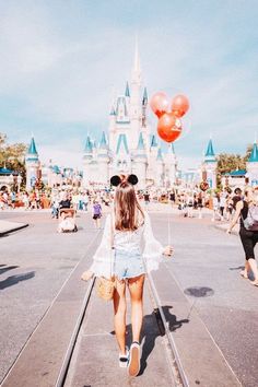 a woman walking down a street with red balloons in the air