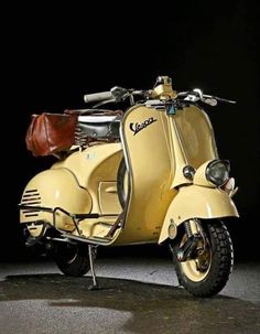 a yellow scooter parked in front of a black background with a brown leather bag on the seat