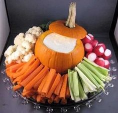 a pumpkin shaped food dish with carrots, celery and radishes