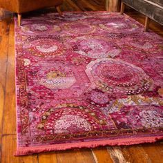 a large pink rug with medallions on it in the middle of a wooden floor