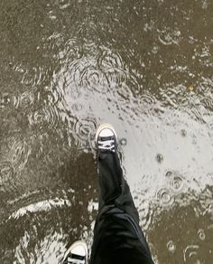 a person standing in the water with their feet up and one foot on the ground